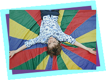 young boy laying on a coloured parachute