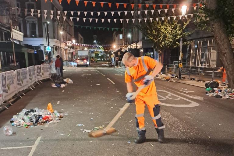 A waste collection worker sweeping at night in Notting Hill
