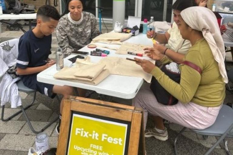 Table showing four people repairing items at the July fix it fest