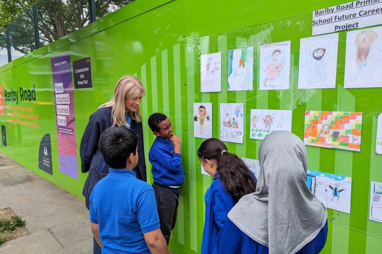 Sof McVeigh and pupils from Barlby Primary looking at their pictures on hoarding
