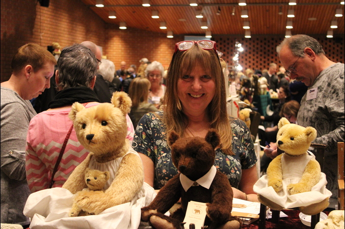 A smiling women holding several teddy bears