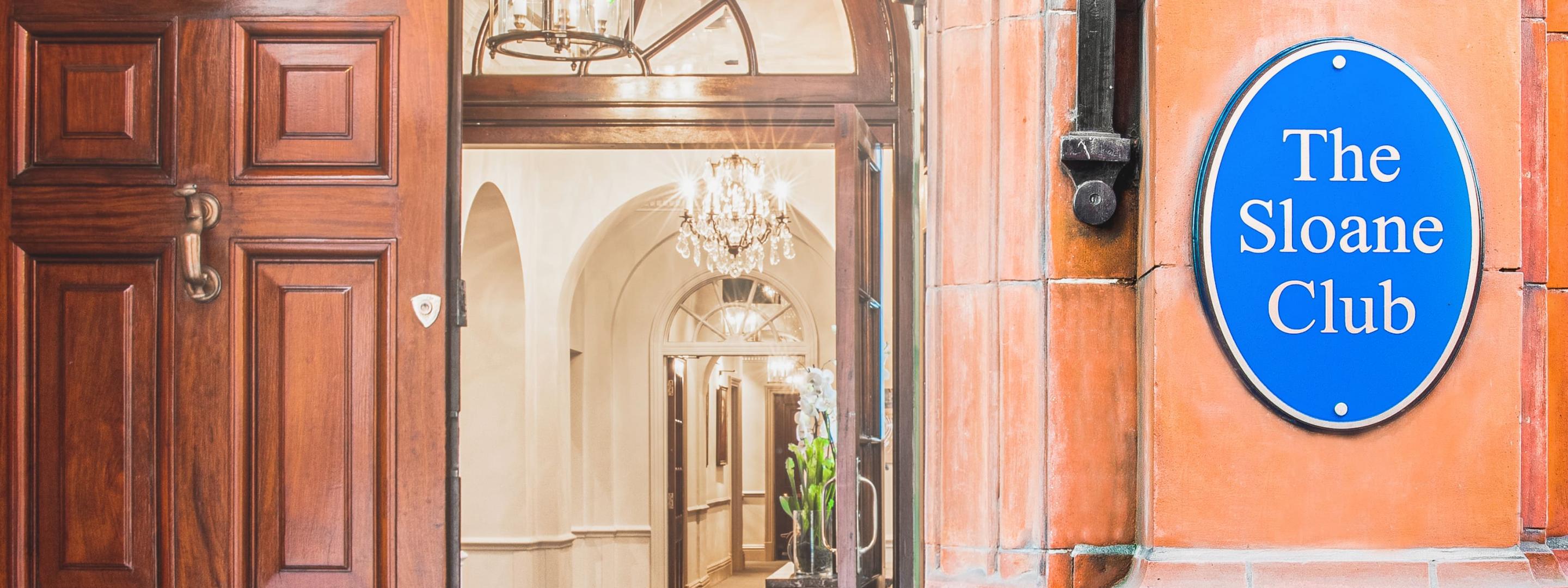 Open door to The Sloane Club with blue plaque on the right reading 'The Sloane Club'