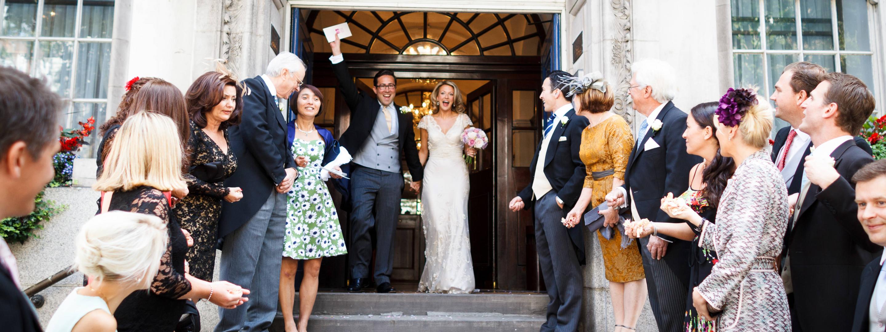 Married couple coming out of building with guests on either side