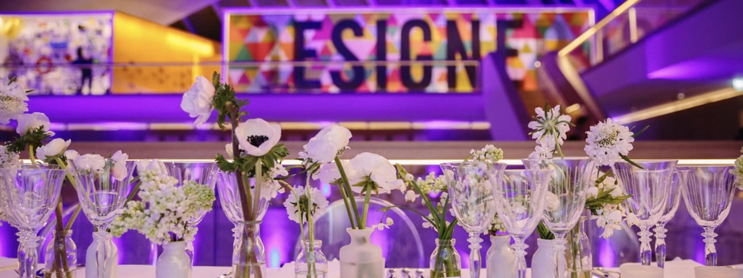 Wind glasses and flowers on dinner table with purple background