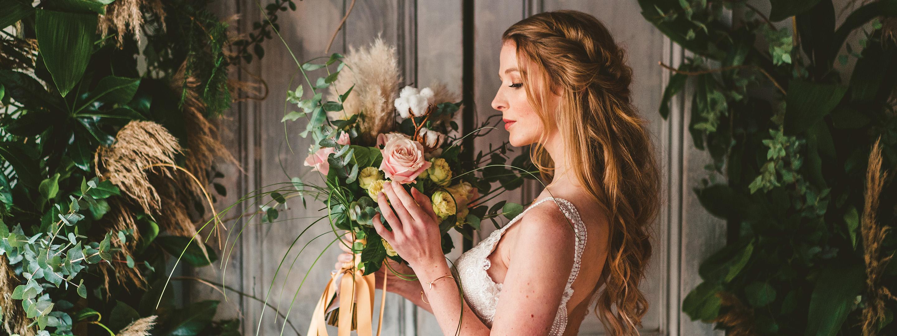 A woman wearing a white wedding dress holding flowers