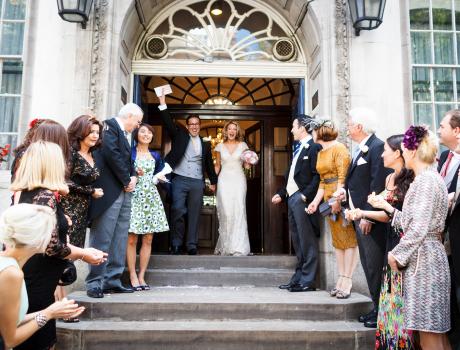 Married couple coming out of building with guests on either side