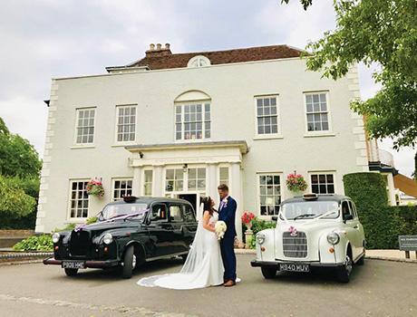 a couple standing outside a stately home