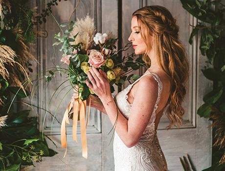 A woman wearing a white wedding dress holding flowers