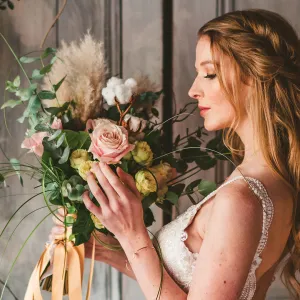 A woman wearing a white wedding dress holding flowers