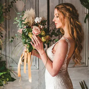 A woman wearing a white wedding dress holding flowers