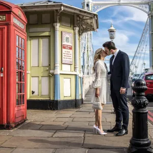 A couple kiss next to a phone box