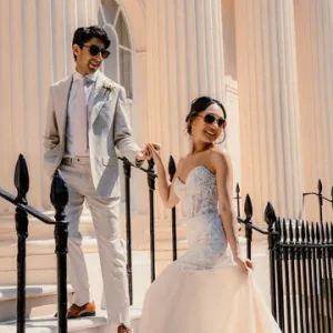 A wedding couple pose by some railings