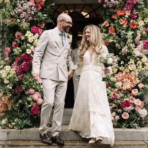 A bride and groom in front of a flower wall