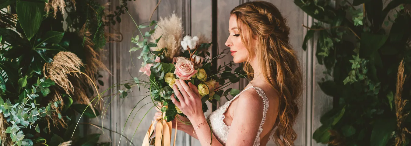 A woman wearing a white wedding dress holding flowers
