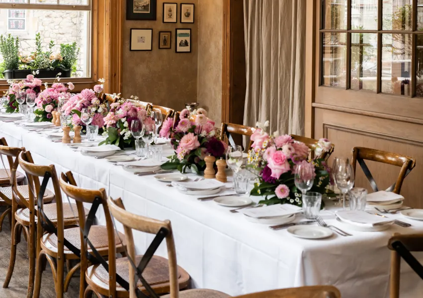 Dinner table set up with flowers, plates and cutlery