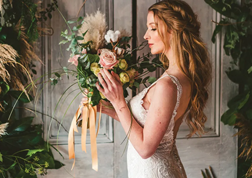 A woman wearing a white wedding dress holding flowers