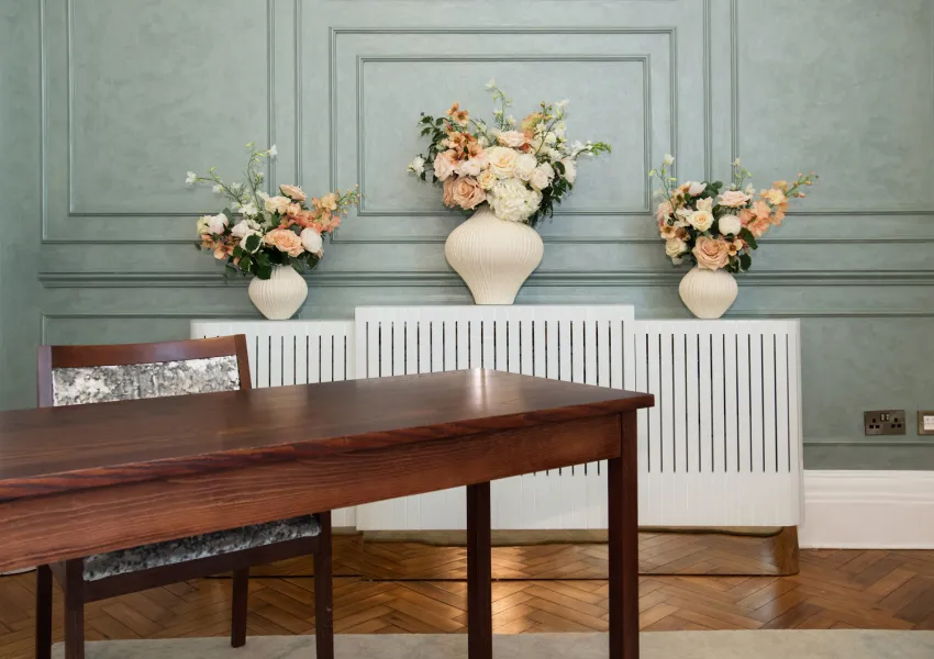 Close view of stylish radiator, floral display and feature wall in Rossetti room.
