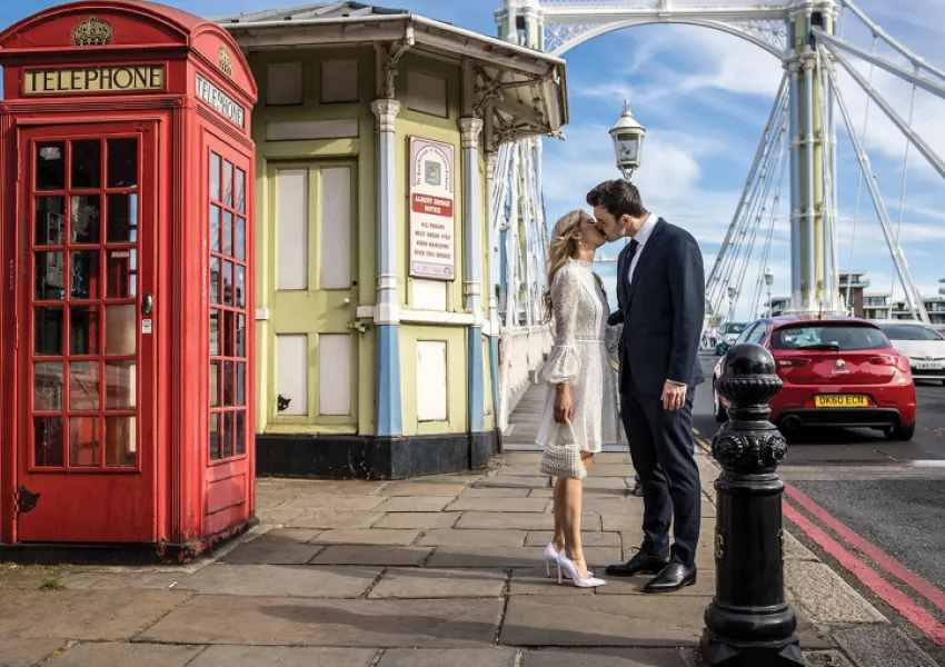 A couple kiss next to a phone box