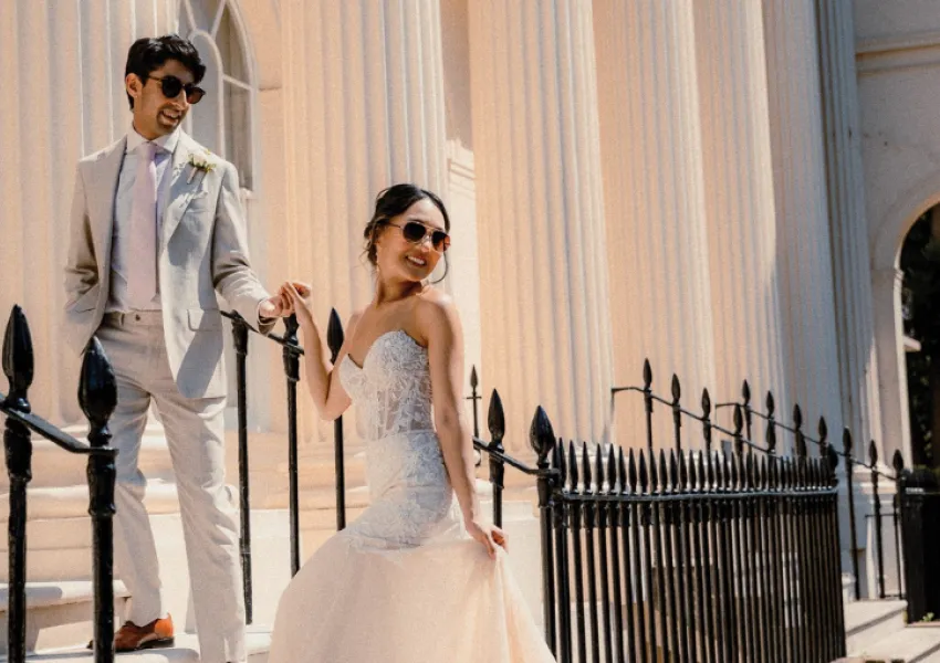A wedding couple pose by some railings