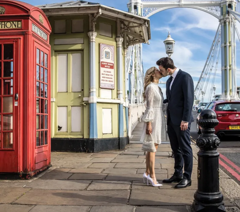 A couple kiss next to a phone box