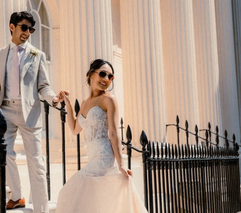 A wedding couple pose by some railings