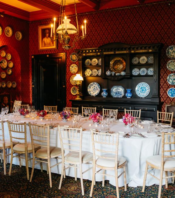A long dining table laid out for dinner in a red dining room