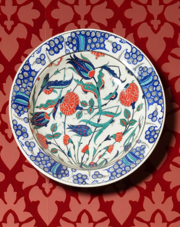 Flower patterns in ceramic plates decorating a red, wallpapered wall
