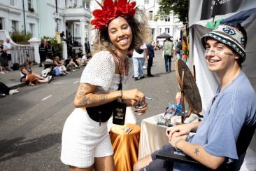 A white man getting his face painted by a female street trader during Notting Hill Carnival.