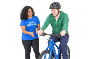 A cycle instructor supporting a person wearing a helmet while learning to ride a bicycle