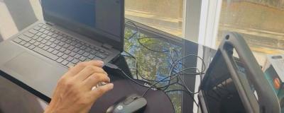 Someone uses a laptop on a glass table top overlooking a road.