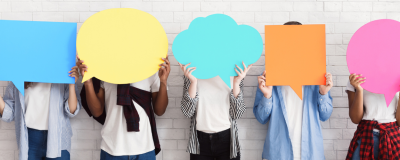 line of people holding up colourful speech bubble signs.