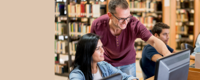 People in a library looking at a computer monitor