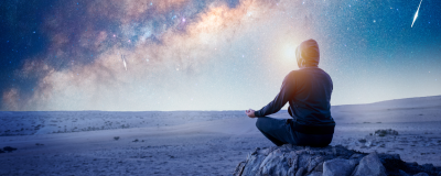 Person meditating under night sky