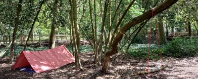 A picture of a red tent in a forest clearing.