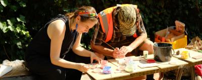 Two people painting pots at a table