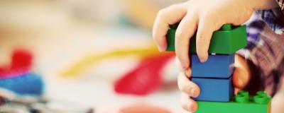 A child's hands building with Lego bricks