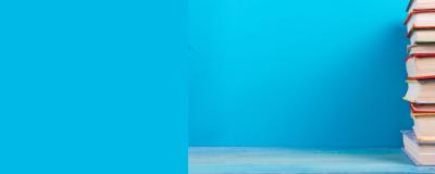 A pile of hardback books stacked against a blue background
