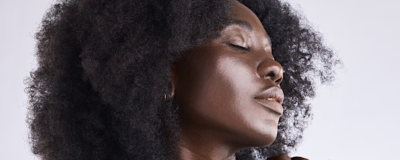 Close up of a woman with natural hair, eyes closed, and a calm expression