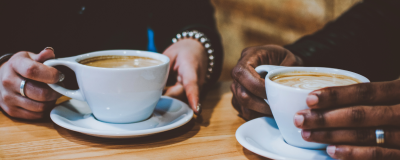 Two people holding cups of coffee