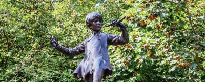 a statue of a boy in front of tree