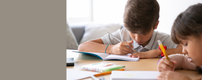 A young boy and girl sat around a table writing together