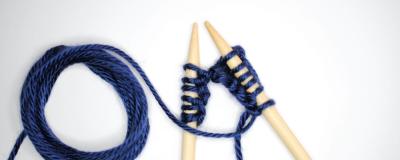 A pair of knitting needles with a row of blue woollen stitches