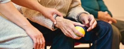an elderly person sat with someone holding their arm