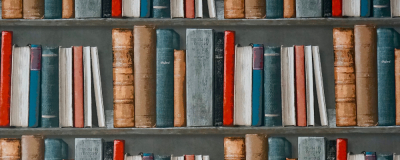 red, brown and blue books on a bookshelf