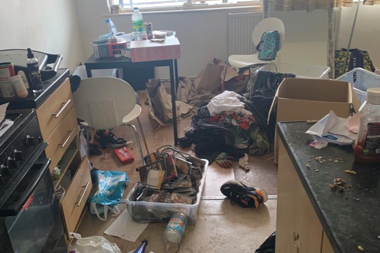 Image of a really messy bedroom with dirt and bin bags everywhere that looks like someone is not living well there