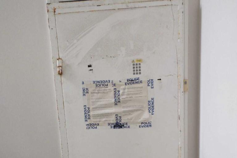 Photo of white door with police tape on it.