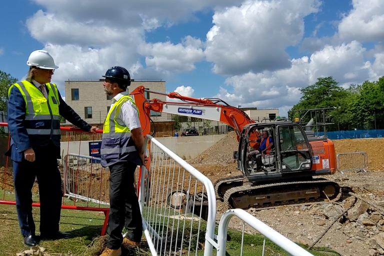 Cllr Kim Taylor Smith speaks to work at Barlby New Homes project, in front of a digger