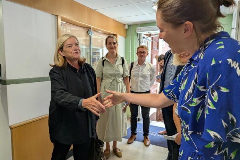 Two people shaking hands while other people look on. 