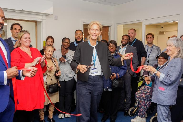 A group of staff and residents gather in the new office as Councillor McVeigh cuts the ribbon