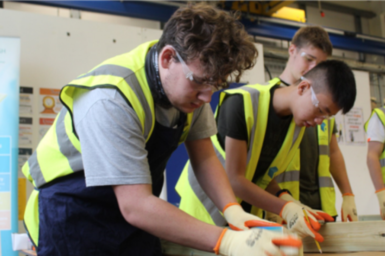 Young people in hi vis jackets on construction course.